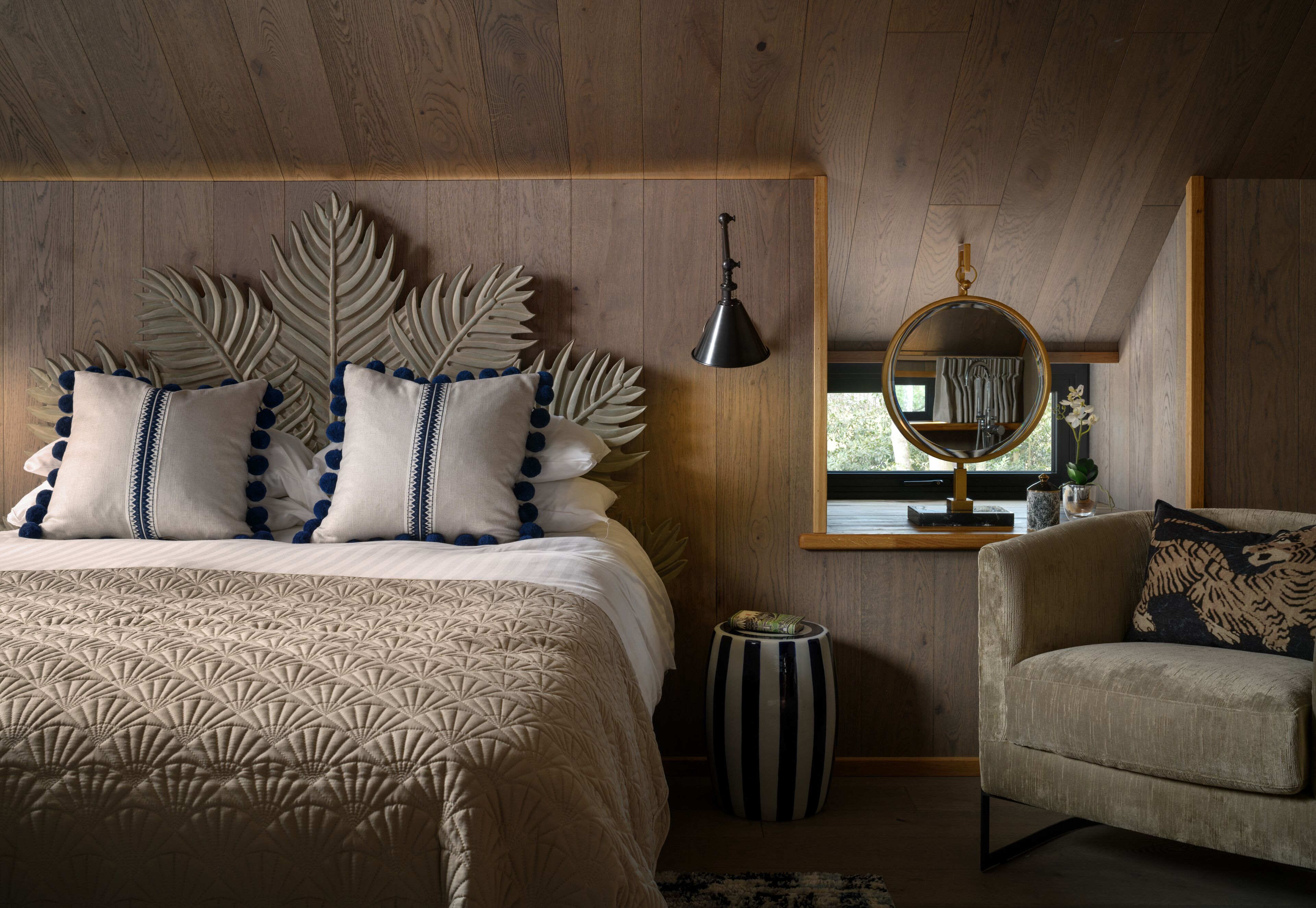 A bedroom with a bed, a chair, a mirror, and a window.