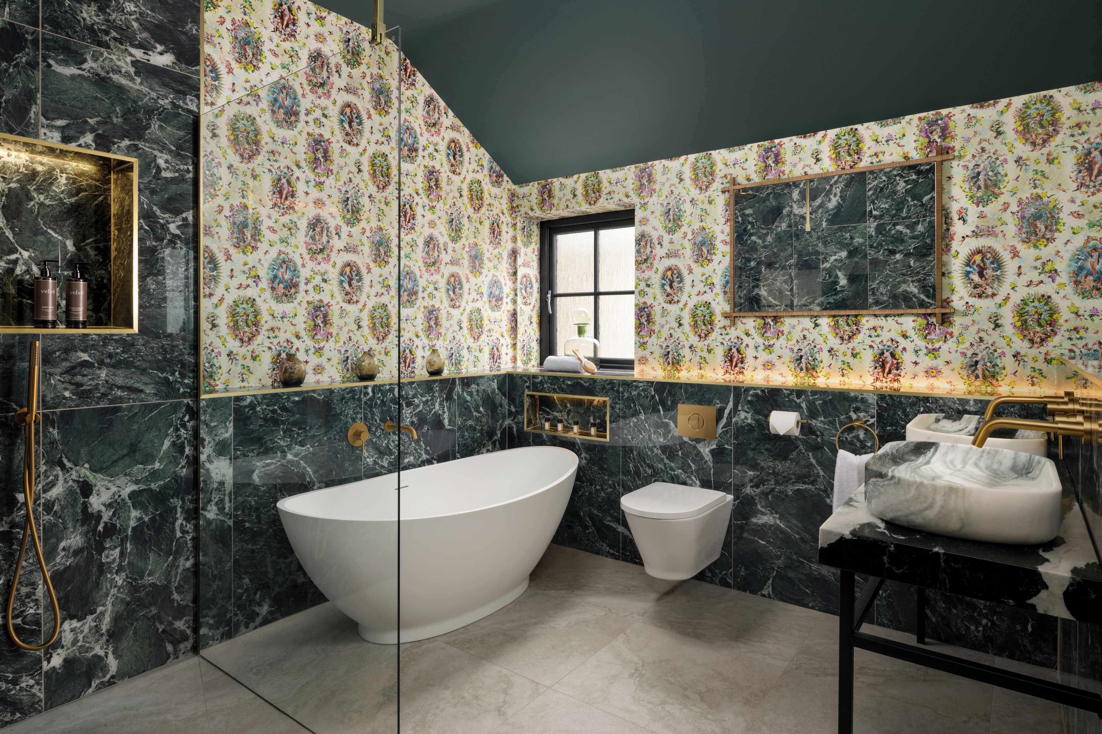 A bathroom with a freestanding bathtub, a toilet, and a sink with a gold faucet.
