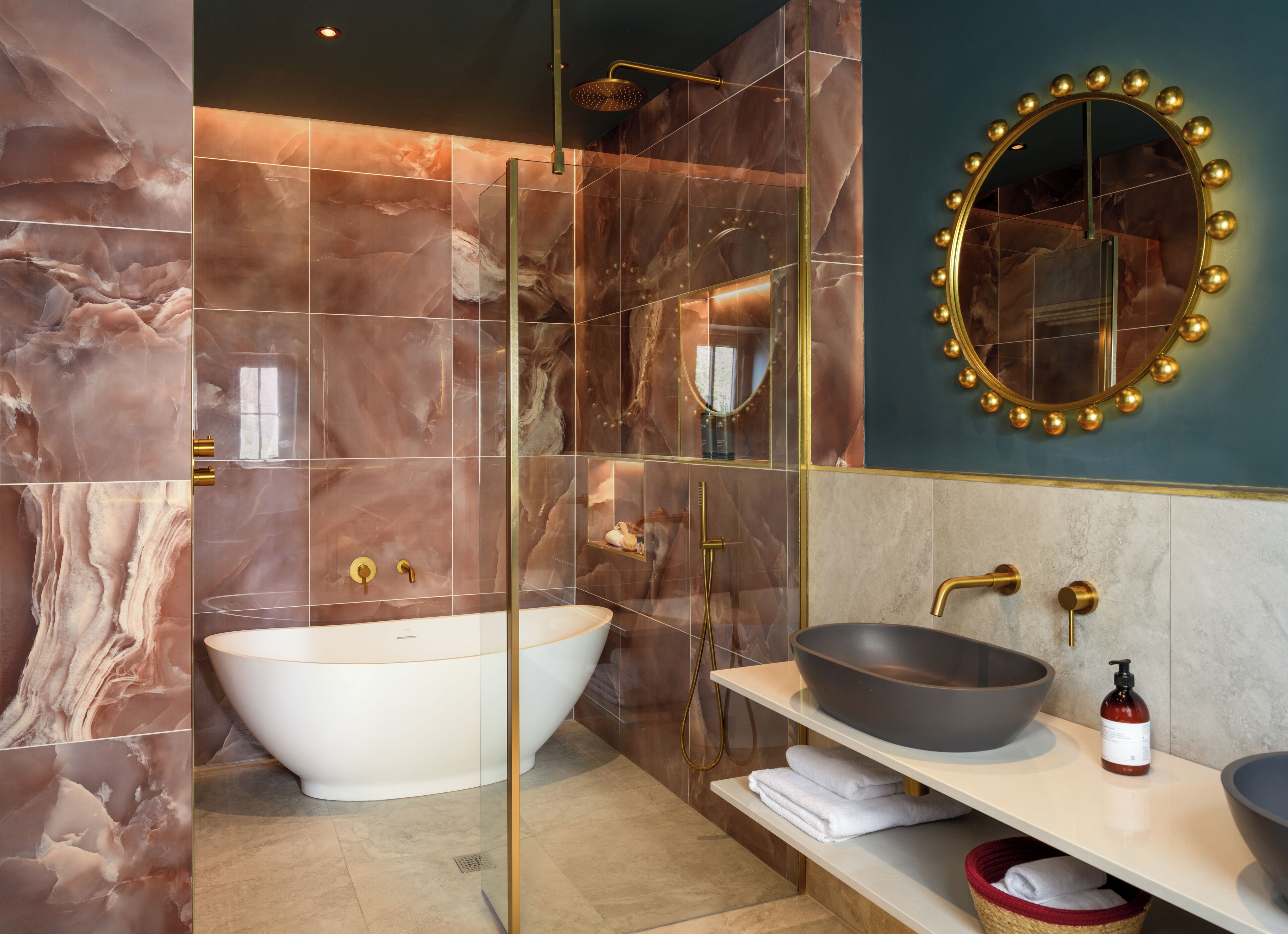 A modern bathroom with a freestanding bathtub, a large mirror with a gold frame, and a vanity with a large bowl sink.