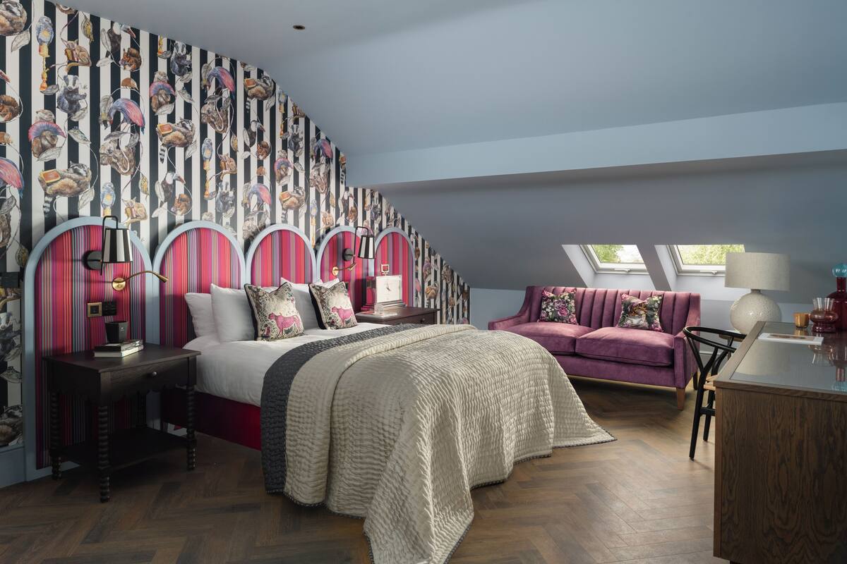Un dormitorio con una cama grande, un sofá, un escritorio y una pared con diseño a rayas.