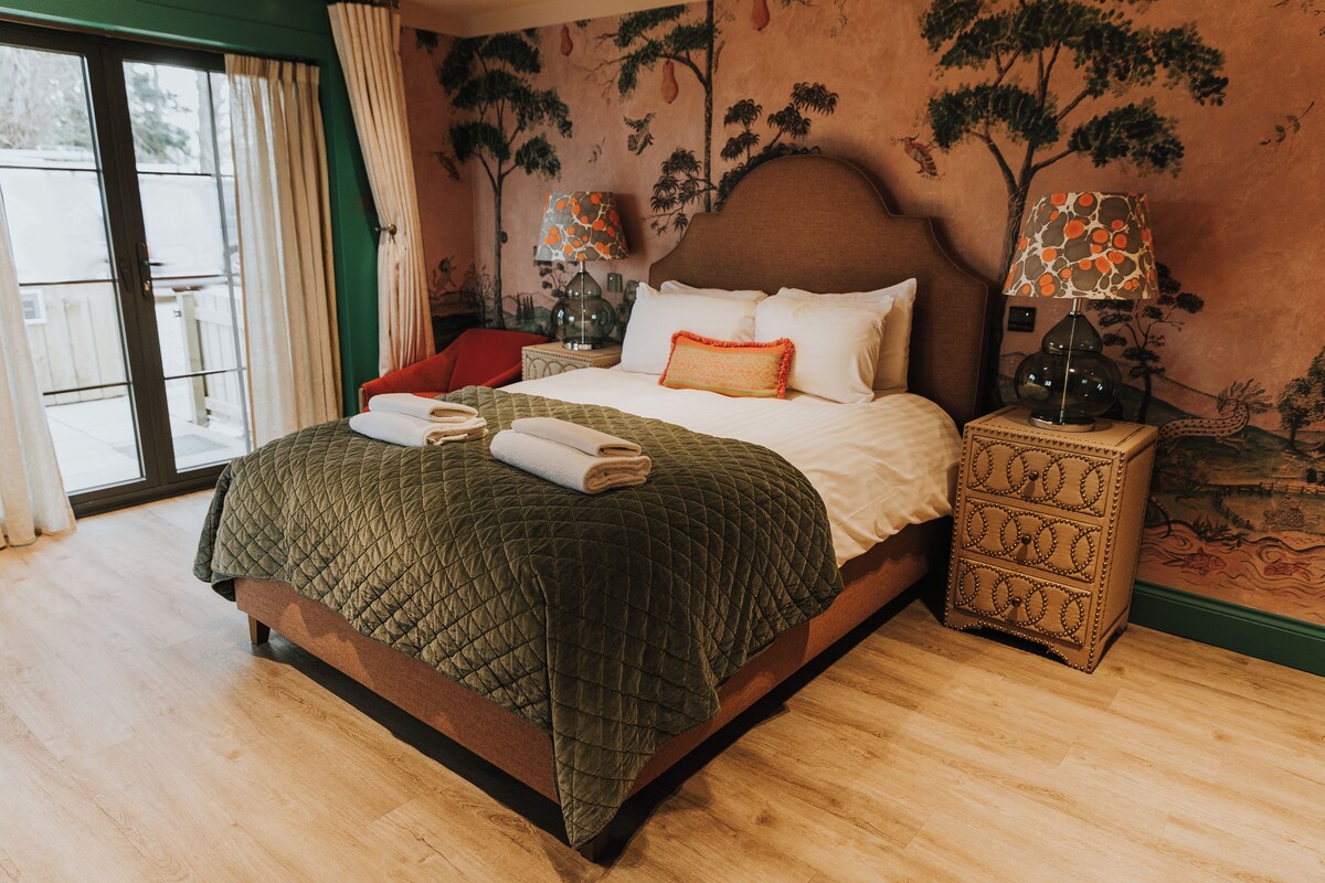 Un dormitorio con una cama grande, una mesita de noche, una silla y una ventana con cortinas.