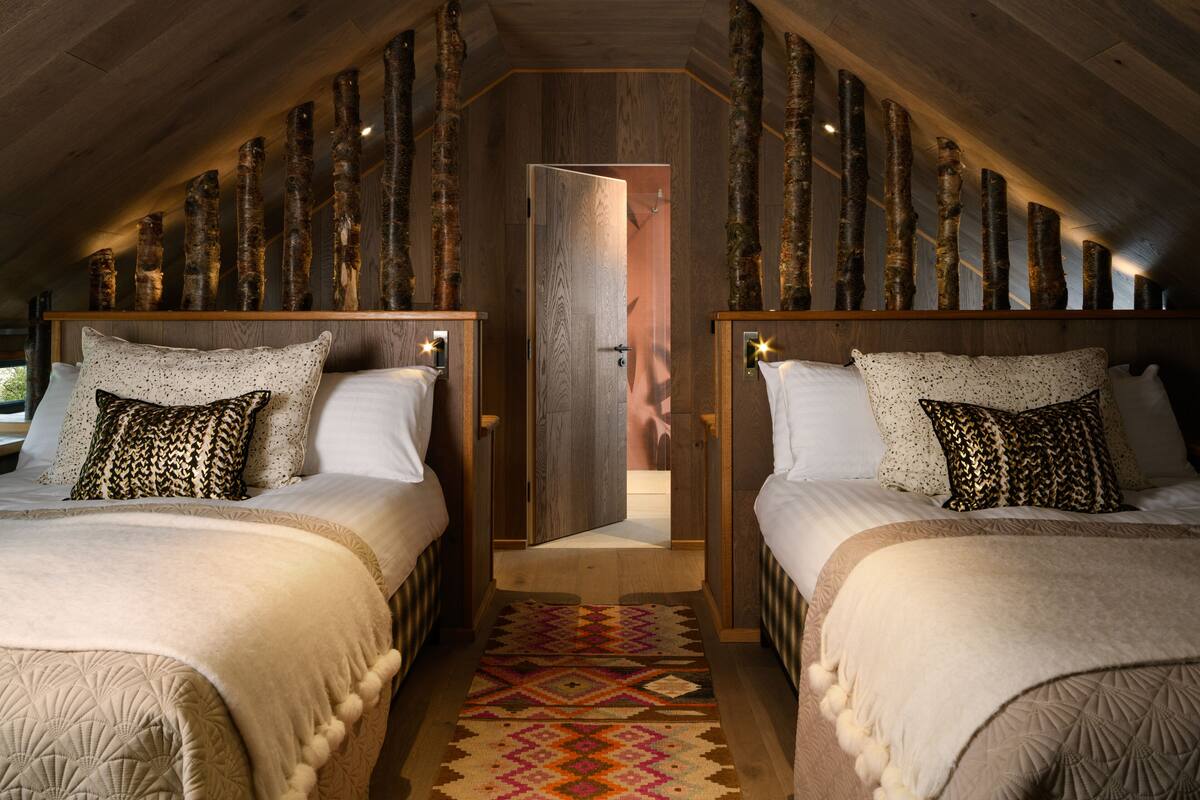 Una habitación con dos camas, un tapete estampado y adornos de madera en las paredes.