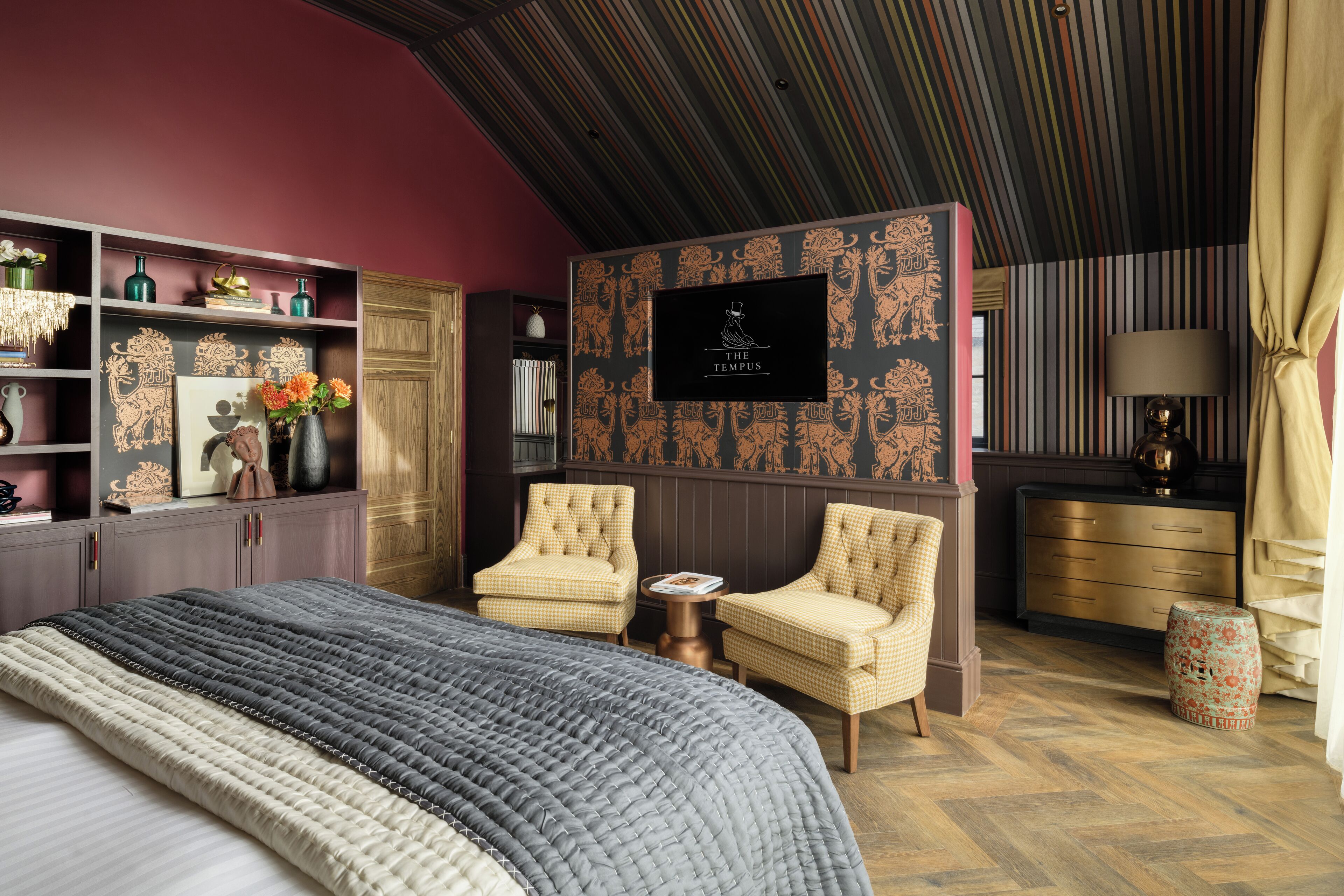 Ein Schlafzimmer mit einem großen Bett, zwei Sesseln, einem kleinen Tisch, einem Fernseher und einem Kleiderschrank.