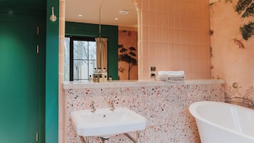Un baño con lavamanos blanco, una bañera independiente y un espejo sobre el lavamanos.