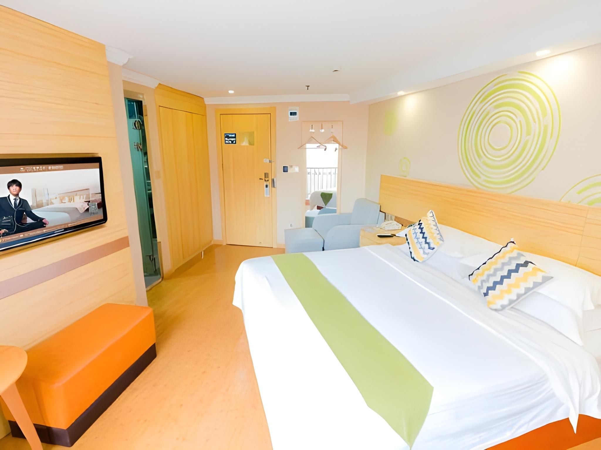 A hotel room with a bed, a TV, a desk, and a chair.