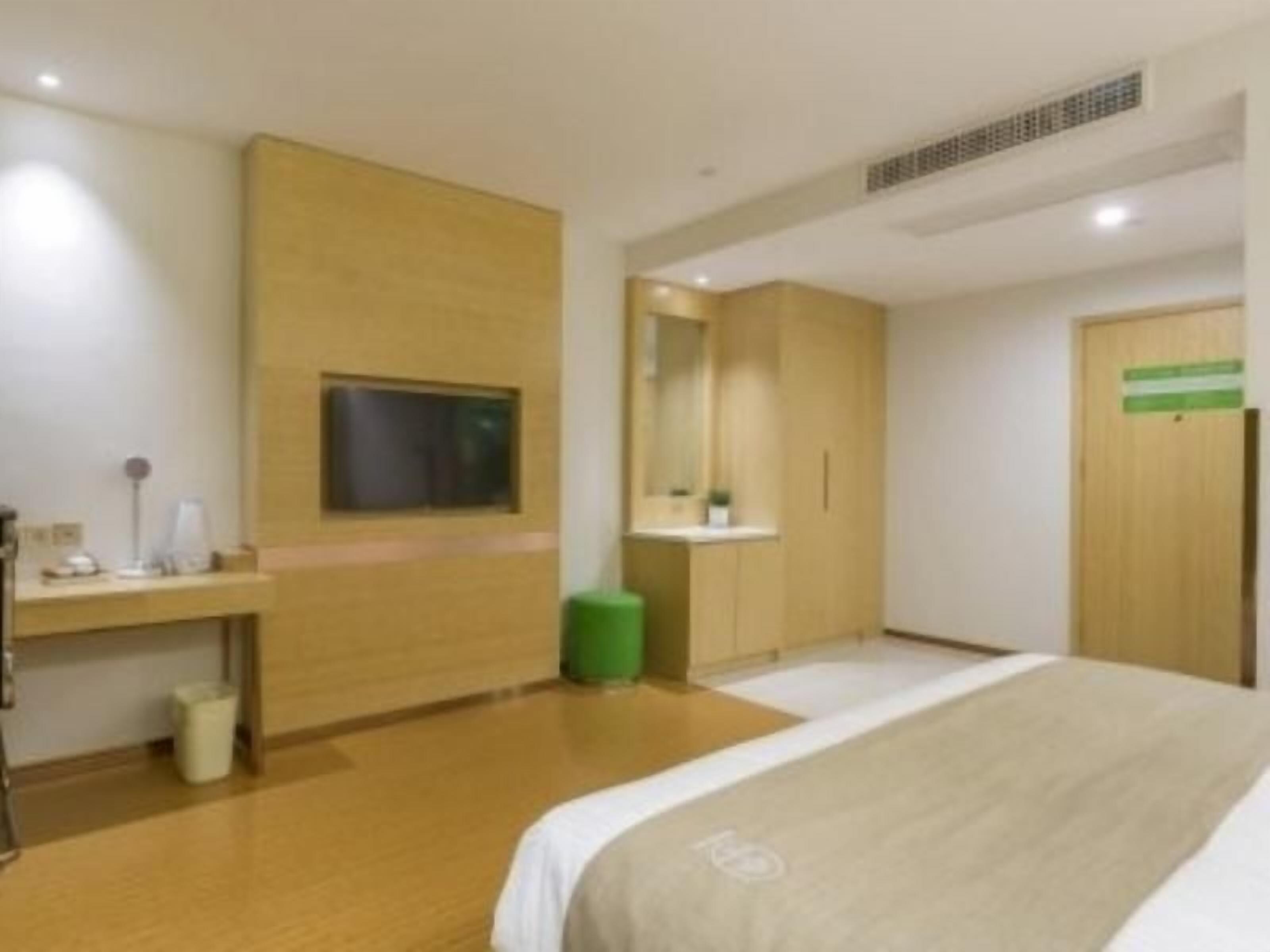 A hotel room with a bed, a desk, a mirror, and a television.