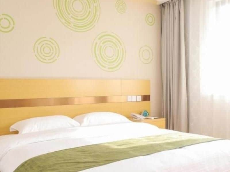 Une chambre d’hôtel avec un lit, une tête de lit, une table de chevet et un mur orné de motifs circulaires.