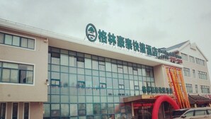 A hotel with a modern facade, large glass windows, and a prominent entrance with a red arch. - Greentree Inn Nantong Qidong Binhai Industrial Park Zone Nanhai Road Express Hotel (Nantong)