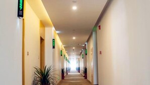 A hotel corridor with directional signs, potted plants, and a carpeted floor. - Greentree Inn Nantong Qidong Binhai Industrial Park Zone Nanhai Road Express Hotel (Nantong)