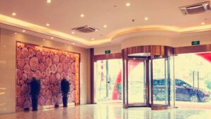 A modern hotel lobby with a polished floor, a decorative wall with circular patterns, and a revolving door leading outside. - Greentree Inn Nantong Qidong Binhai Industrial Park Zone Nanhai Road Express Hotel (Nantong)