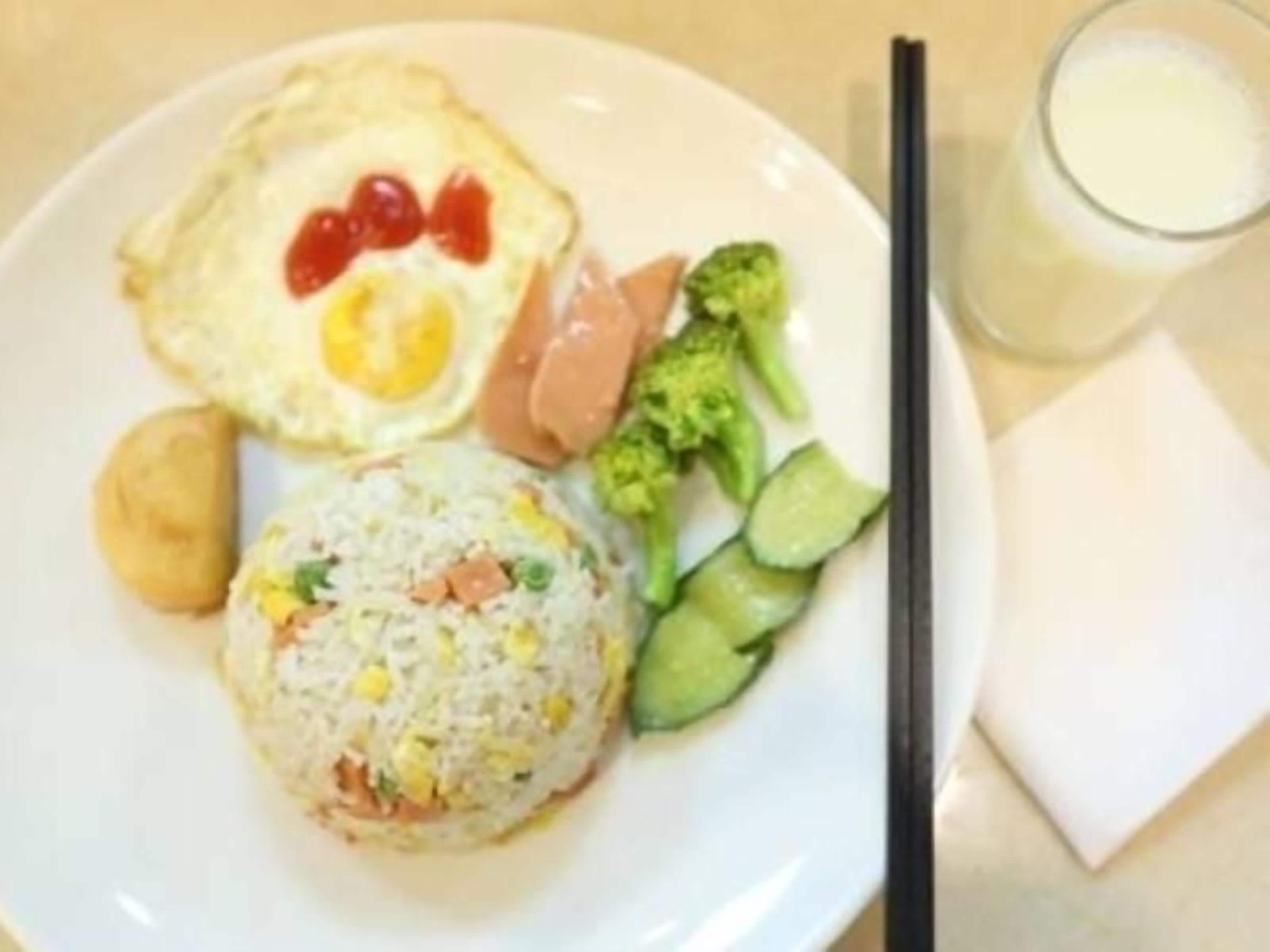 A plate with fried egg, sausage, and vegetables, and a glass of milk.
