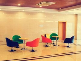 Un vestíbulo con piso pulido, una mesa de recepción y sillas coloridas.