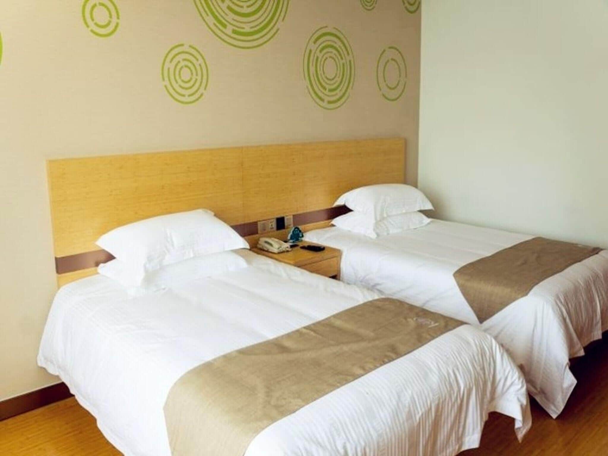 A hotel room with two beds, a wooden headboard, and a wall with circular patterns.