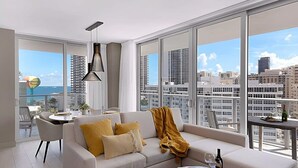 Una sala moderna con sofá, mesa de centro y comedor. Amplios ventanales ofrecen vistas a la ciudad y al océano.