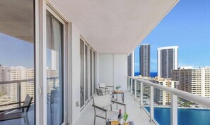A balcony with a table, chairs, and a view of tall buildings.