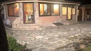 A stone patio with a stone house featuring large windows and a small attached structure. - Villa in Chia 5 minutes from the most beautiful beaches (Chia)