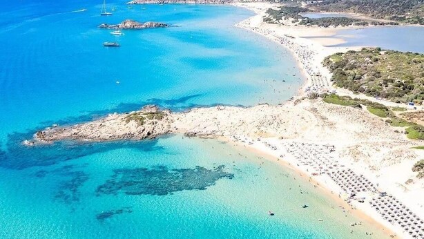 An aerial view of a coastal area with clear turquoise waters, a sandy beach, and rocky outcrops. - Villa in Chia 5 minutes from the most beautiful beaches (Chia)