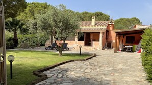 A stone pathway leading to a house with a tiled roof, surrounded by greenery and a palm tree. - Villa in Chia 5 minutes from the most beautiful beaches (Chia)