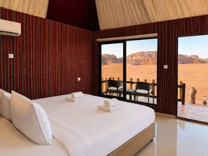 A hotel room with a large bed, a view of the desert, and a balcony with chairs. - Shaheen Camp wadi rum (Wadi Rum)