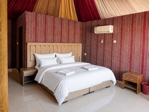 A bedroom with a large bed, two bedside tables, a wall-mounted air conditioner, and a red curtain. - Shaheen Camp wadi rum (Wadi Rum)