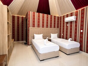 A hotel room with two beds, a large padded headboard, and a red patterned wall. - Shaheen Camp wadi rum (Wadi Rum)