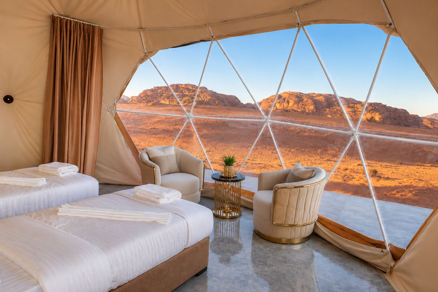 A tented room with two beds, two chairs, and a small table.