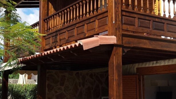 Ein Holzbalkon mit einer Steinmauer und einem weißen Zaun.