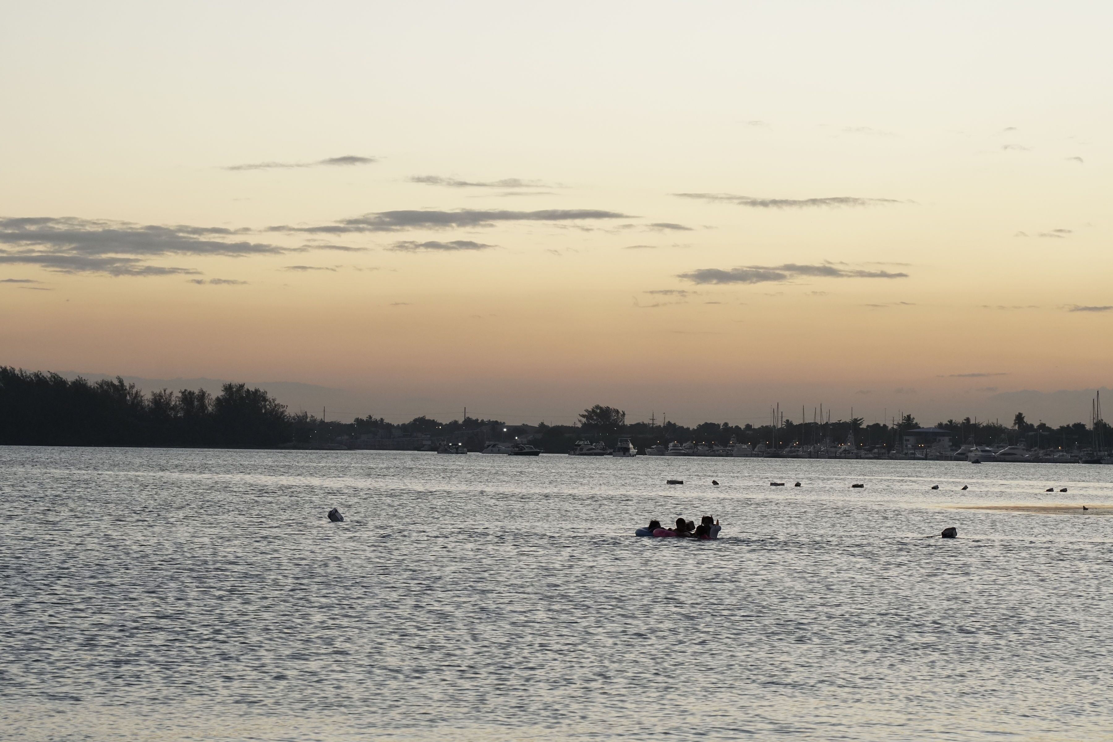A calm body of water with boats and a distant shoreline.