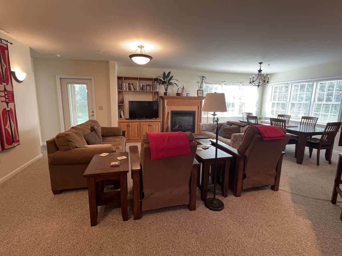 A living room with a sofa, chairs, a coffee table, a fireplace, and a television.