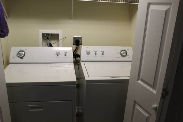 A laundry room with two front-loading washers and dryers, a white door, and a utility wall with a power outlet. - 14080 Mountain View | First Floor Condo! (Mercersburg)