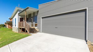 Ein modernes, zweistöckiges Haus mit verdeckter Veranda, Garage und gepflegtem Rasen.