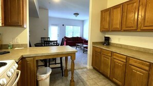 Una cocina con armarios de madera, una mesa de comedor y una estufa.
