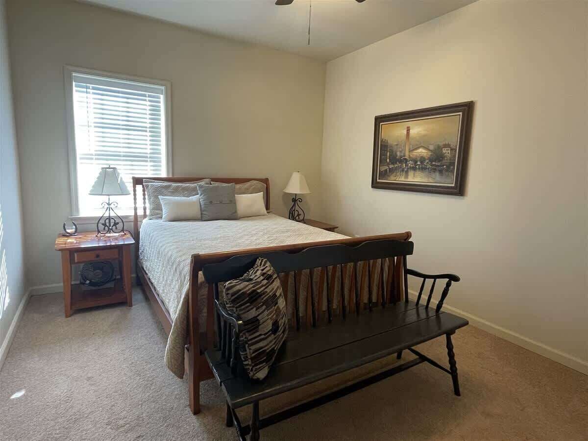 A bedroom with a bed, a bench, a nightstand, a lamp, and a painting on the wall.