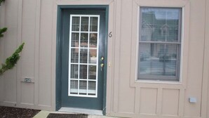 Une maison avec une porte vert foncé, une fenêtre avec des stores et le chiffre « 6 » peint sur le mur.