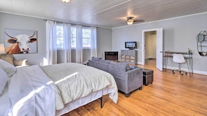 A spacious room with a large bed, a gray sofa, a TV, and a desk with a chair. - Birmingham Vacation Rental: 9 Miles to Downtown! (Birmingham)