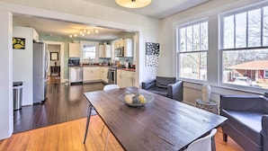 A modern kitchen with white cabinets, a dining area with a dark wooden table, and large windows offering a view of the outside. - Birmingham Vacation Rental: 9 Miles to Downtown! (Birmingham)