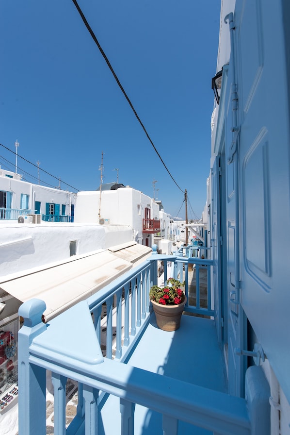 Un balcon avec une balustrade, un pot de fleurs et un ciel bleu dégagé.
