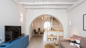 Uma sala de estar moderna com uma televisão, um armário azul e uma escada que leva a uma área de jantar.