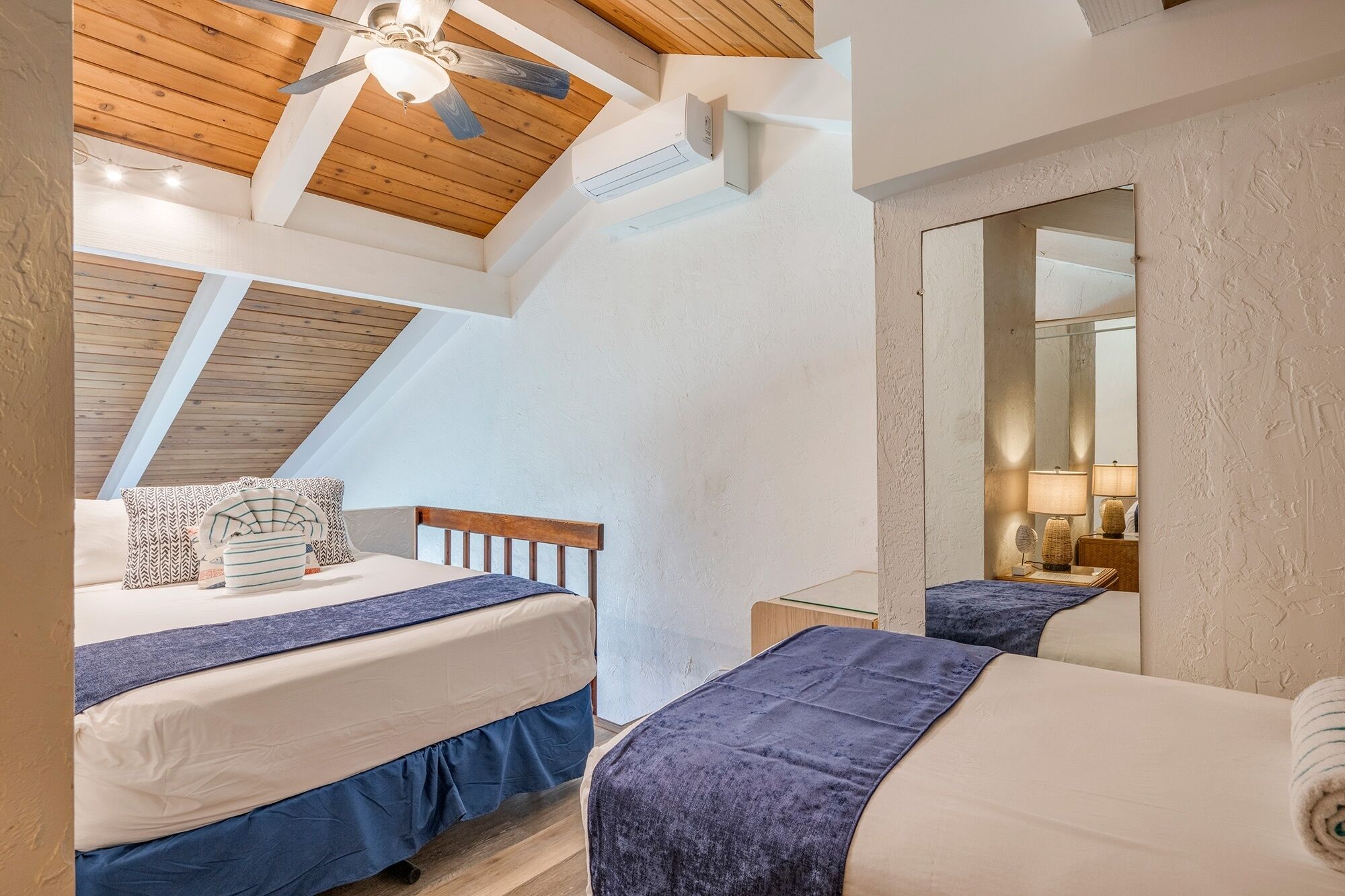 Een slaapkamer met twee bedden, een plafondventilator en een dakraam.