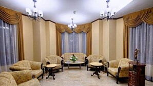 Una habitación con cuatro sillones, un sofá, una mesita de centro y un aparador.