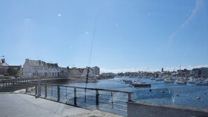 En hamn med båtar, en bro och byggnader längs strandpromenaden.