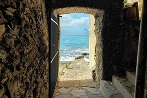 A stone archway leading to a coastal view with a boat on the shore.