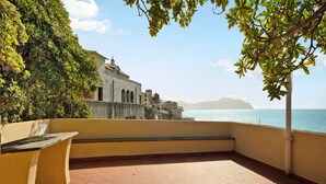 Una terraza con vista al mar y un edificio al fondo.