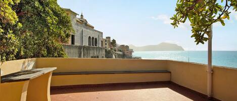 A terrace with a view of the sea and a building in the background.