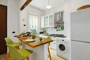 Cocina compacta con una isla de madera, lavadora y refrigerador.