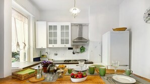 Una cocina con armarios blancos, encimera de madera, un fregadero y un refrigerador.