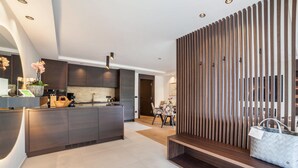 Une cuisine moderne dotée d’un îlot central, de meubles de rangement aux couleurs sombres et d’une cloison en bois.