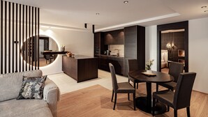 Une cuisine moderne dotée d’un îlot central, d’un coin repas avec des chaises et d’un canapé agrémenté d’un coussin à motifs floraux.