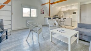 Un salón moderno con un sofá blanco, una mesa de centro blanca y sillas de mimbre.