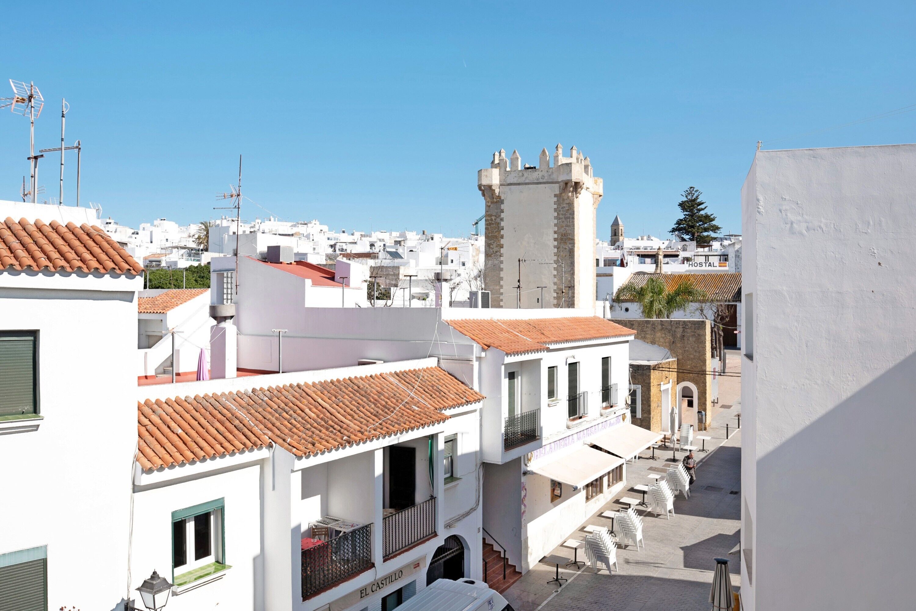 Un edificio blanco con techo de tejas rojas, balcones y una torre.